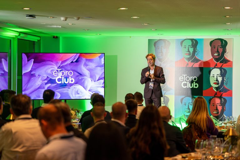Ponente en el escenario de la cena de gala de eToro, con obras de Warhol de fondo