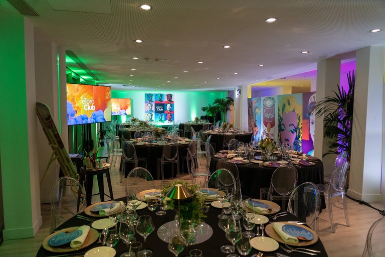 Montaje de las mesas de la cena de gala de eToro, con iluminación verde y obras de Warhol