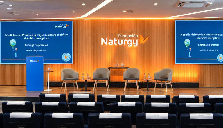 El auditorio preparado para la ceremonia, con el atril, las butacas del escenario y las pantallas de la Fundación Naturgy