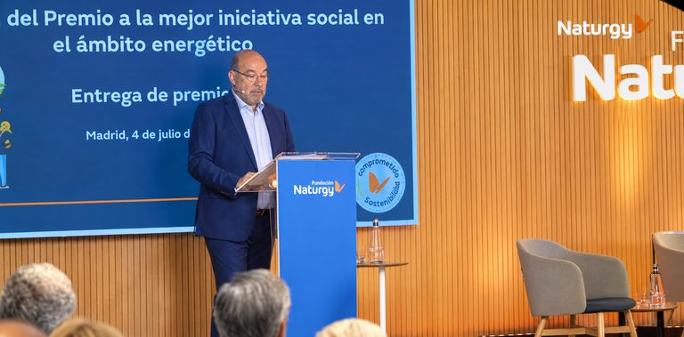 Un ponente en el atril, junto a la pantalla de la entrega de premios
